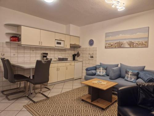 un soggiorno con un divano blu e un tavolo di Ferienwohnung Seesternchen am Deich a Norden