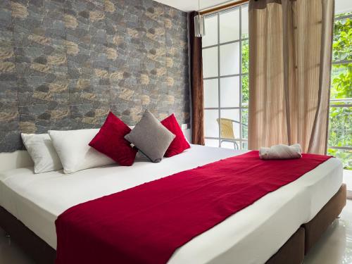 a bedroom with a large bed with red and white pillows at Montes De Beraka in Minca