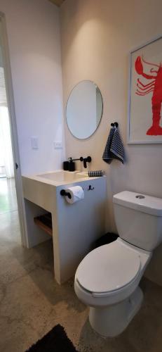 a bathroom with a toilet and a sink with a mirror at Casa Remy - Walk to the Beach and stay in a private compound! Pool, Kitchen, AC, Wi-Fi in Mal País