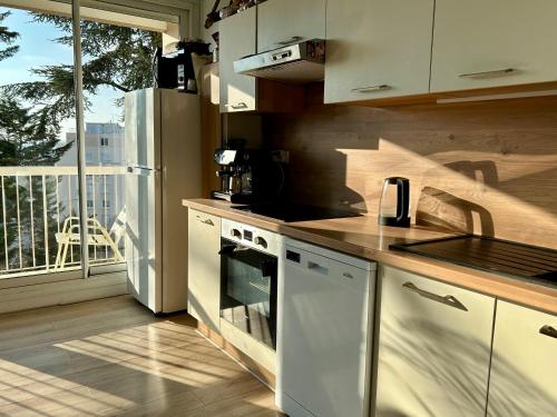Il comprend une cuisine équipée d'une cuisinière. - un four supérieur à côté d'un balcon dans l'établissement Appartement 24H du Mans, au Mans