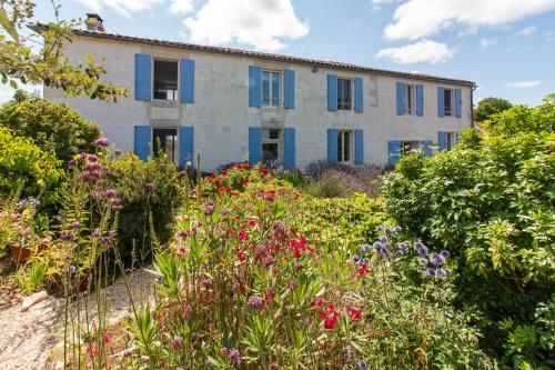 una casa con le persiane blu e un giardino con i fiori di Charming countryside retreat a Macqueville