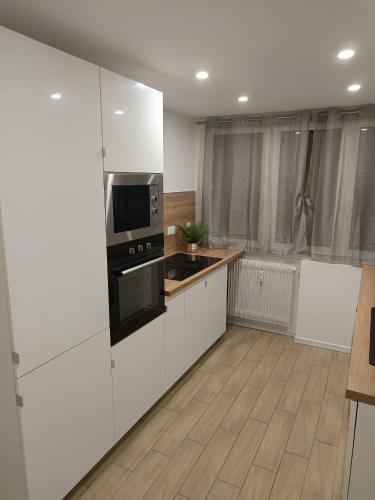 La cuisine est équipée de placards blancs et d'un four micro-ondes noir. dans l'établissement Superbe Appartement !, à Saint-Étienne