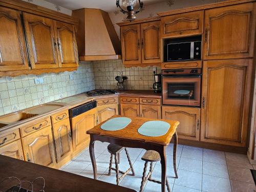 une cuisine avec des placards en bois et une table avec des tabourets dans l'établissement Chez Gaby, à Montgreleix