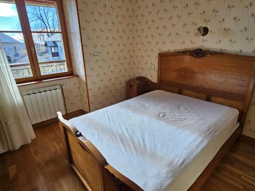 - une chambre avec un lit avec un cadre en bois et une fenêtre dans l'établissement Chez Gaby, à Montgreleix