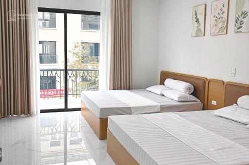 a hotel room with two beds and a balcony at Moonstone Homestay & Cafe - Vinhomes Ocean Park 2 in Hòa Bình