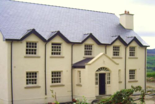 a white house with a black roof at Tinnakilly Lodge, Spaciously luxurious home near Aughrim Wicklow in Aughrim