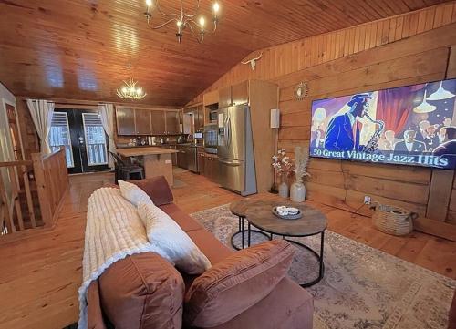 a living room with a couch and a large tv at The Log Haus An Countryside Escape in Pembroke