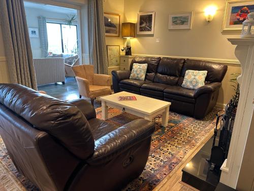 a living room with a leather couch and a coffee table at Teach Cruachan Large-Group Holiday Home in Dooagh