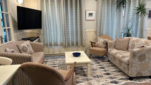 a living room with furniture and a flat screen tv at Teach Cruachan Large-Group Holiday Home in Dooagh