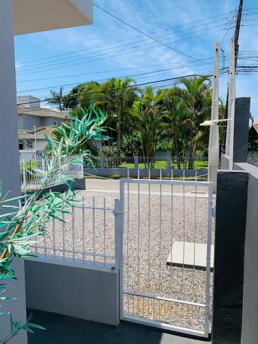 a gate to a driveway with palm trees at Flet dos sonhos in Florianópolis