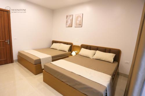 a bedroom with two beds and a door to a room at Moonstone Homestay & Cafe - Vinhomes Ocean Park 2 in Hòa Bình