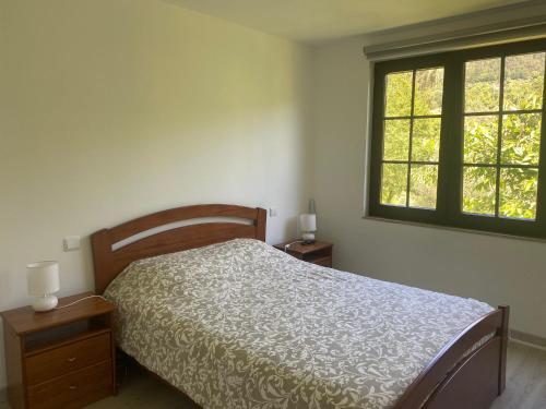 ein Schlafzimmer mit einem Bett und zwei Fenstern in der Unterkunft Leiras da Cachada - Gerês in Valdosende