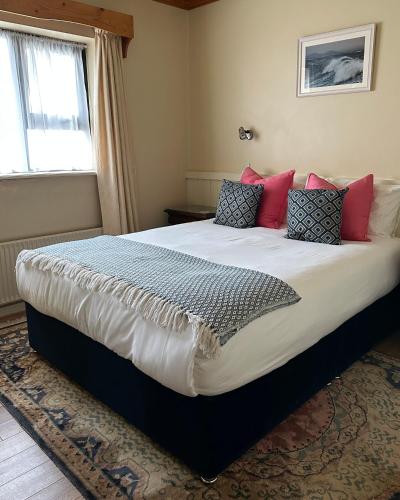 a bedroom with a large bed with pink and blue pillows at Teach Cruachan Large-Group Holiday Home in Dooagh