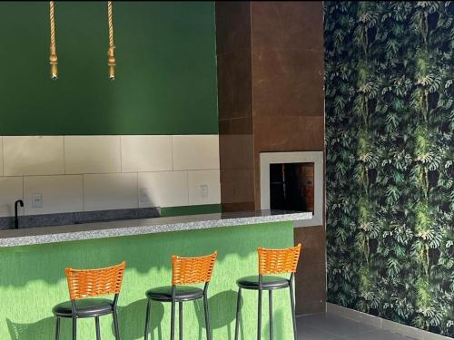 a bar with four orange chairs and a green wall at VILLAGE Vista do Cruzeiro ITAITU in Jacobina