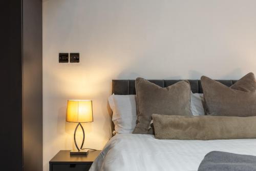 a bedroom with a bed with a lamp on a table at Bradford Luxury Central Apartment in Bradford