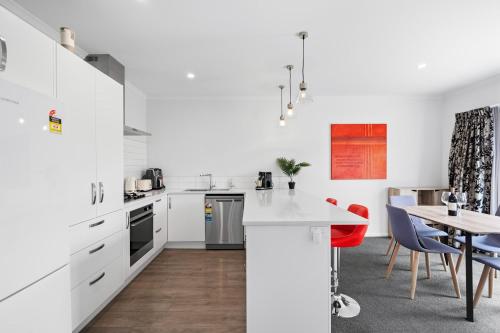 a kitchen with white cabinets and a table with chairs at Contemporary 3 Bed Townhouse Near CBD & Hospital in Hamilton