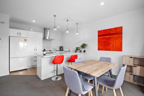 a kitchen with a wooden table and red chairs at Contemporary 3 Bed Townhouse Near CBD & Hospital in Hamilton