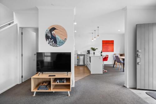 a living room with a tv and a kitchen at Contemporary 3 Bed Townhouse Near CBD & Hospital in Hamilton