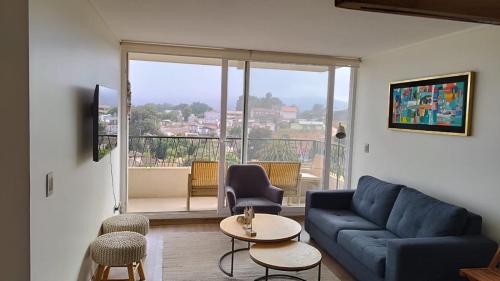 un soggiorno con un divano blu e un balcone di Precioso departamento con vista a la playa a Papudo