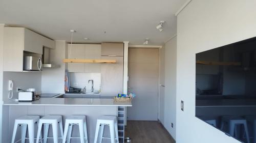 una cucina con bancone e sgabelli di Precioso departamento con vista a la playa a Papudo