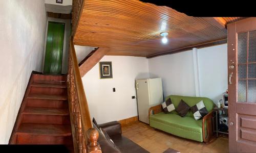 a living room with a staircase and a green couch at Hermosa Casa en la Calendaria - centro histórico de la ciudad in Bogotá