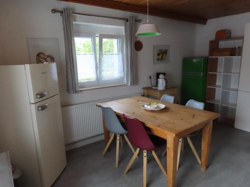 a kitchen with a wooden table and chairs and a refrigerator at Monteurwohnung bei Crailsheim Feuchtwangen in Fichtenau
