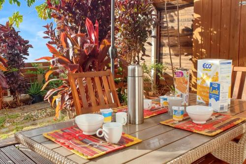 a wooden table with cups and bowls on it at Appartement avec vue sur mer à Saint-Paul, 50 m², Terrasse in Saint-Paul