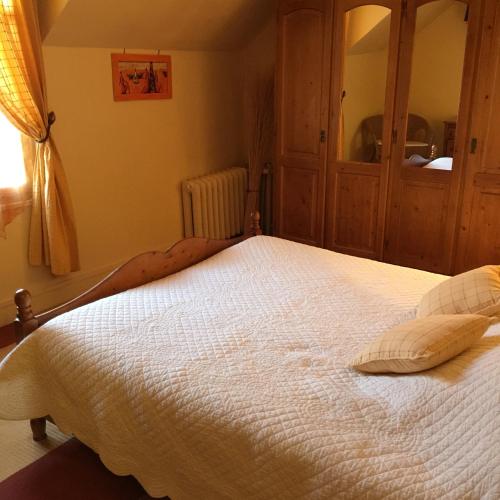 a bedroom with a large bed with white sheets at Maison d'hôtes la Ferme De L'abbaye in Juilly