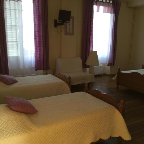 a hotel room with two beds and a chair at Maison d'hôtes la Ferme De L'abbaye in Juilly