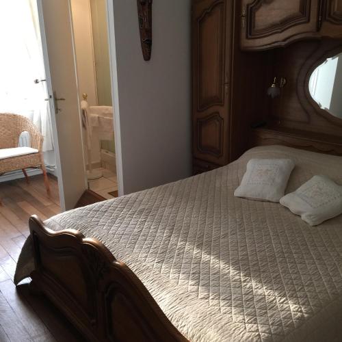 - une chambre avec un grand lit en bois et 2 oreillers dans l'établissement Maison d'hôtes la Ferme De L'abbaye, à Juilly
