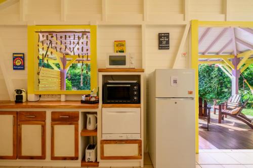 a kitchen with a microwave and a refrigerator at Chez Marie & Philippe Ti'Kaz Vanille in Cadet