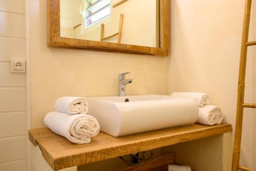 a bathroom with a sink and towels on a shelf at Chez Marie & Philippe Ti'Kaz Vanille in Cadet