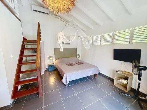 - une chambre avec un lit et une télévision dans l'établissement Location saisonnière dans résidence avec piscine, à Les Trois-Îlets