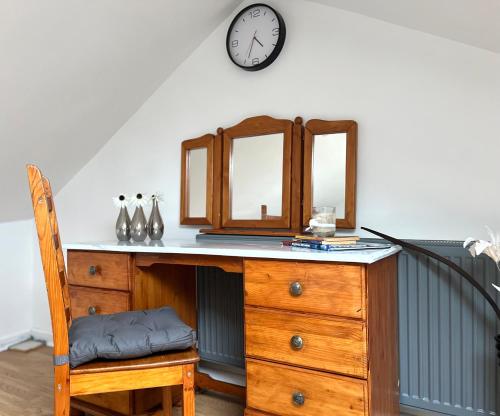 a desk with a chair and a clock on the wall at Cosy 3BDR In Levenshulme-Close To Manchester City Centre And Stockport Town- Free Parking- WiFi in Manchester