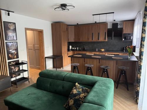 a living room with a green couch and a kitchen at Apartament Elegancka Husarska in Wałbrzych