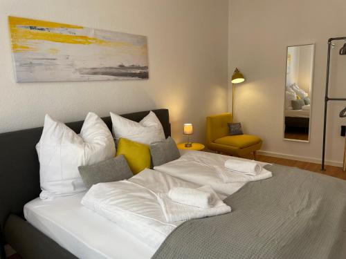 a bedroom with a bed with white sheets and yellow pillows at LS01 Deluxe Apartment, voll ausgestattet, zentral, groß in Magdeburg