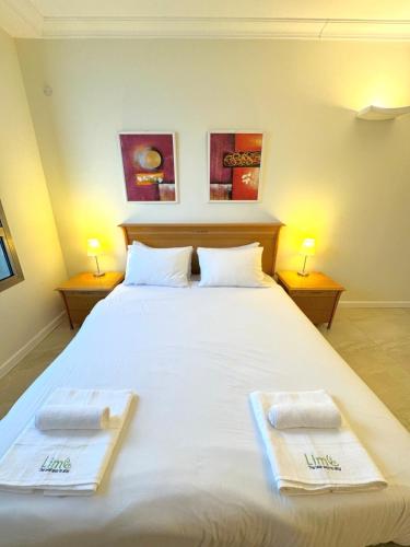 Un dormitorio con una gran cama blanca con toallas. en Apartment on the beach BY LIME, en Haifa
