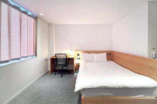 a bedroom with a bed and a desk and a window at Mangrove Jeju City in Jeju