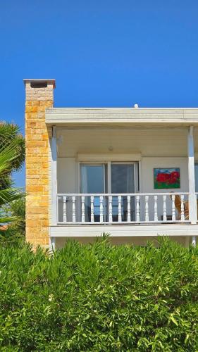 a house with a white balcony and a tree at Villa Mira - 3BR Villa with Panaromic Sea View in Datca