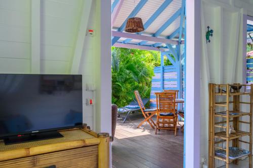 a living room with a tv and a porch with chairs at Chez Marie & Philippe Ti'Kaz Cannelle in Cadet