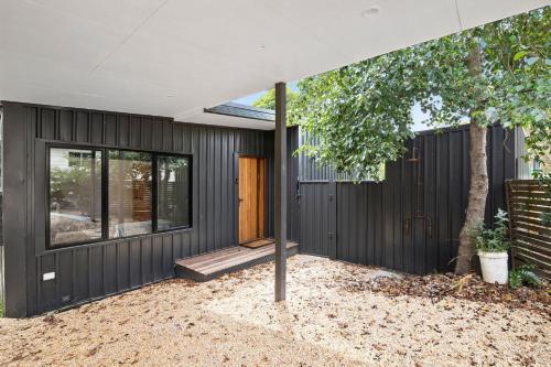 Ein Haus mit einem schwarzen Zaun und einem Baum in der Unterkunft Riverside Escape in Anglesea