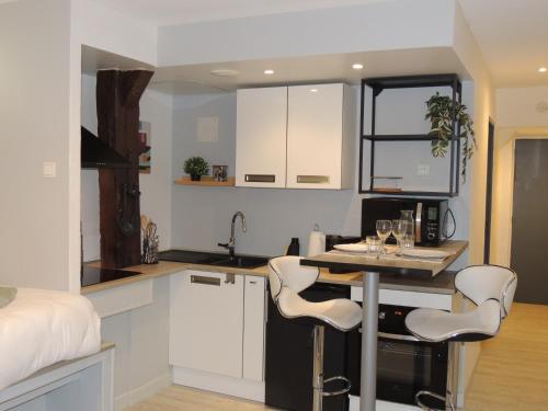 une cuisine avec des armoires blanches et une table et des chaises dans l'établissement L'Escale, studio, hyper-centre historique, Netflix, à Laval