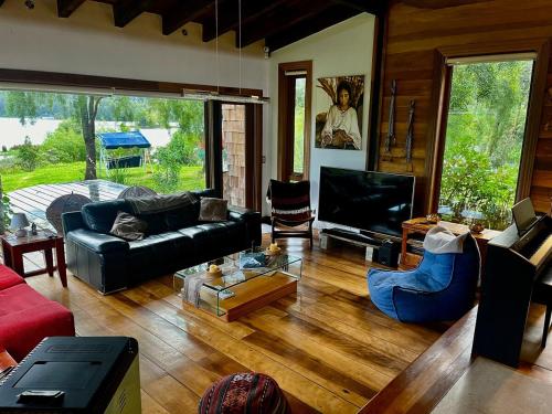 a living room with a black couch and a tv at La Casa Del Lago in Puerto Octay