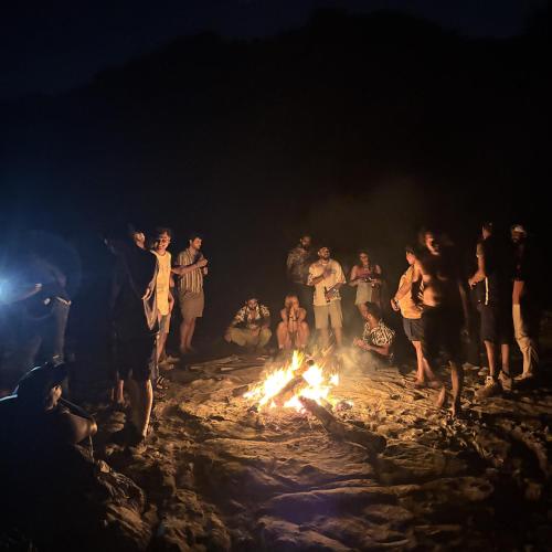 a group of people standing around a fire on the beach at Tamasha Goa Vagator in Vagator