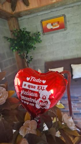 a red heart shaped balloon sitting on top of flowers at Chalé Paradiso Biazolli in Farroupilha