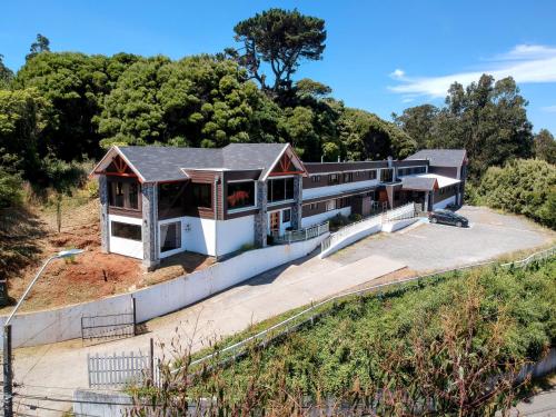 una casa en la ladera de una colina con árboles en Hotel Bután Coronel, en Coronel