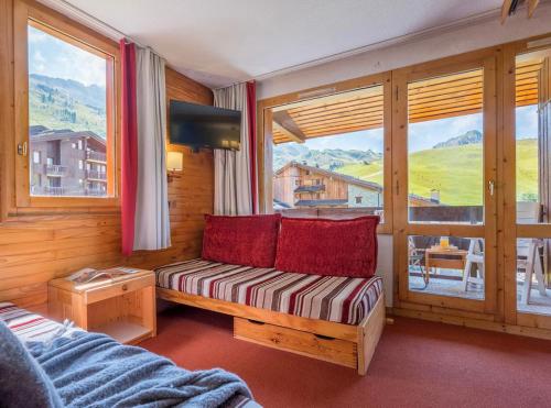 un salon avec un canapé et une grande fenêtre dans l'établissement Les Terrasses Blanches - Appartement Belle Plagne - 4 personnes - Exposition plein Sud - Sur pistes, à La Plagne Tarentaise