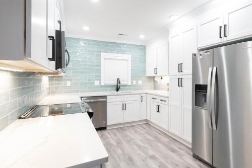 a kitchen with white cabinets and a stainless steel refrigerator at King Beds Hot Tub Arcade Gas Grill Firepit Winston in Winston-Salem