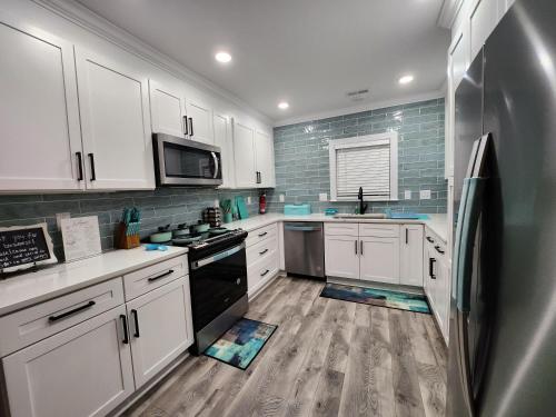 a kitchen with white cabinets and a stainless steel refrigerator at King Beds Hot Tub Arcade Gas Grill Firepit Winston in Winston-Salem