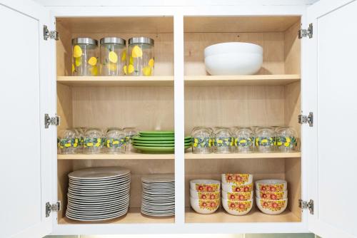 a cupboard filled with plates and bowls and dishes at King Beds Hot Tub Arcade Gas Grill Firepit Winston in Winston-Salem